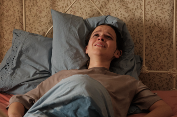 Een jonge vrouw ligt huilend in bed