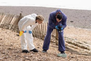 Twee forensisch pathologen bukken en maken een foto van een blauwe slipper