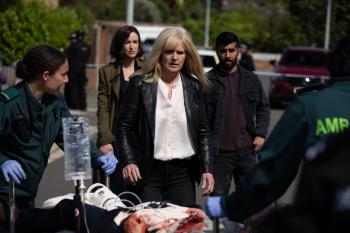 Blonde vrouw loopt naar brancard met medisch team op straat.