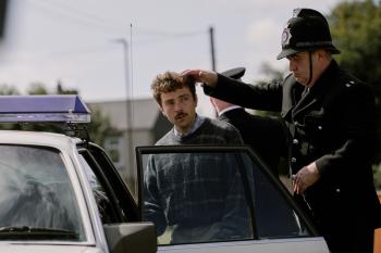 Politieagent begeleidt man in trui naar politieauto.