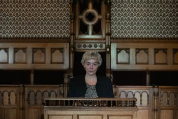 Vrouw in een houten katheder in een traditionele rechtszaal.