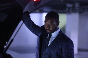 Man in pak bij kofferbak auto