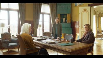 3 mensen voeren een lastig gesprek aan een grote tafel in een landhuis