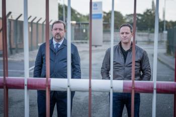 Twee mannen staan achter een hek