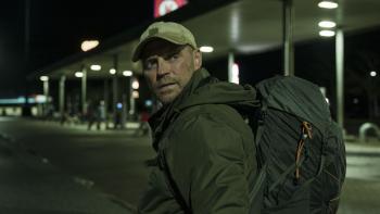 Man met rugtas kijkt achterom