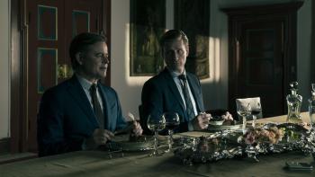 Twee mannen zitten in het donker aan tafel 