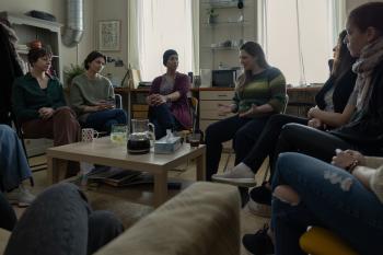 Een groep vrouwen zit in een woonkamer 