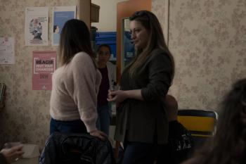 Een vrouw kijkt geschrikt door een deuropening 