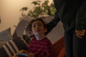 Een jongetje zit op de bank kijkt omhoog 