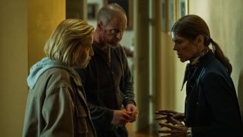 Drie mensen staan gespannen bij elkaar, iemand is gewond