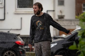 Een man staat in de regen