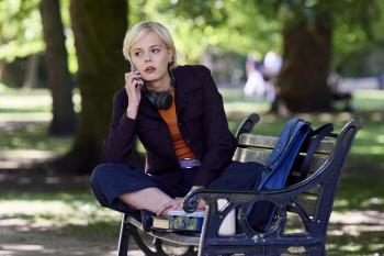 Een vrouw zit bellend op een bankje in het park