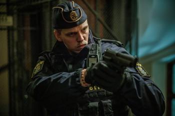 Een man in officieel politieuniform richt zijn pistool 