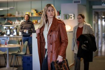 Een blonde vrouw met een rode jas loopt gehaast