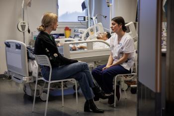 Een man ligt in het ziekenhuis, naast zijn bed praten twee vrouwen met elkaar