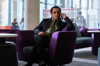 Een man in pak is op een paarse stoel aan het bellen