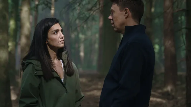 Vrouw kijkt man aan ze staan in een bos.