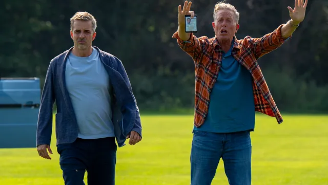 Flemming en Dan zijn op een open grasveld en Dan houdt zijn armen in de lucht en schreeuwt