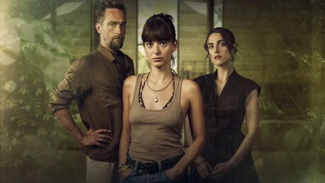 Drie personen met serieuze blikken in een wazige achtergrond, een man en twee vrouwen.