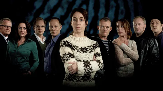 Groep mensen in donkere kleding, vrouw in lichte trui centraal, donkere achtergrond.