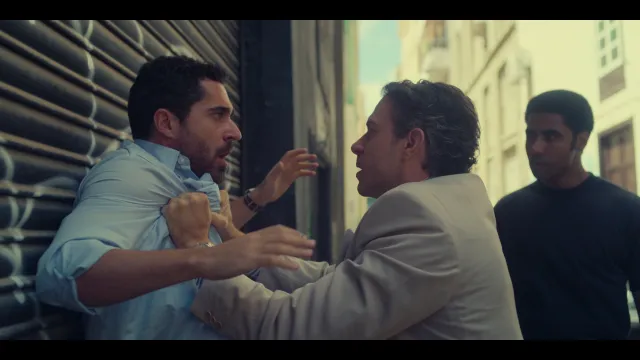 Twee mannen in een intense discussie op straat, derde man kijkt toe.