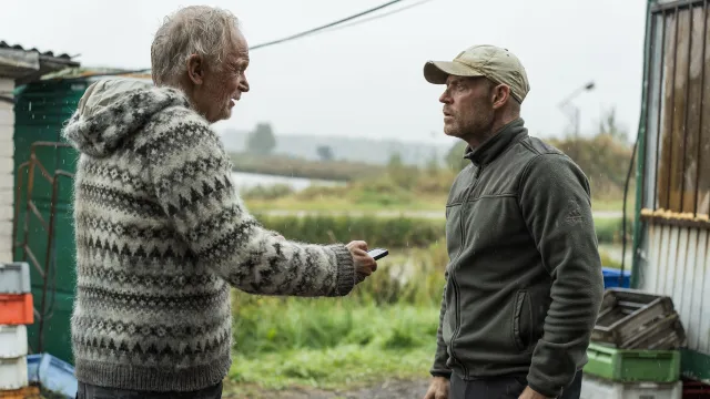 Man geeft buiten een telefoon aan een andere man