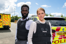 Twee politieagenten uit The Tower hebben hun handen in hun zakken en kijken naar de camera