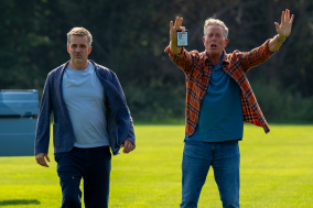 Flemming en Dan zijn op een open grasveld en Dan houdt zijn armen in de lucht en schreeuwt