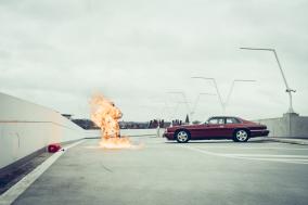 Rode auto op verlaten parkeergarage, met vlammen en een jerrycan op de grond.