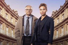 Twee mensen in zakelijke kleding staan voor een rij oude gebouwen bij zonsondergang.