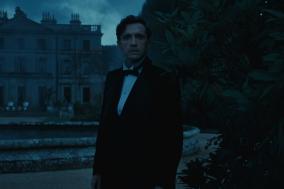 Man in pak in het donker voor een groot landhuis