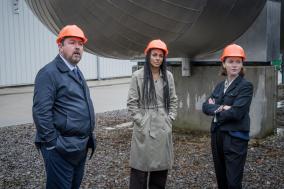 Drie mensen met een oranje helm op een bouwplaats
