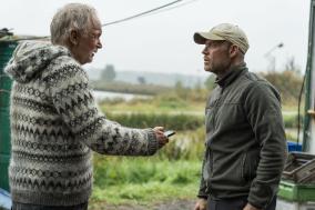 Man geeft buiten een telefoon aan een andere man