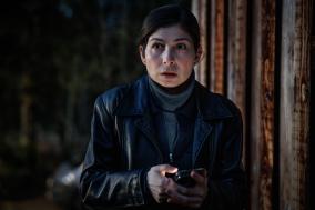 Een man zit in het bos achter haar telefoon