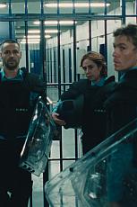 Beveiligers in uniform met schilden in een gang met tralies.