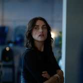 Vrouw kijkt zijwaarts in een modern interieur met vage achtergrond.