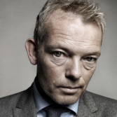 Man in pak schuin kijkend in de camera