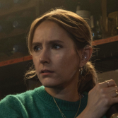 Vrouw kijkt bezorgd naar links in een sfeervolle ruimte.